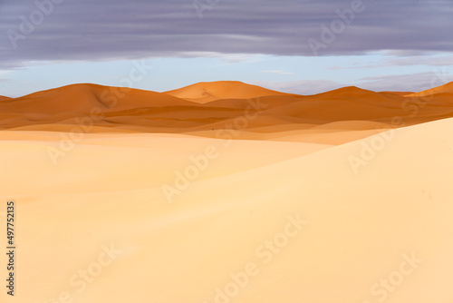 Paesaggio desertico con dune di sabbia alte e sfondo cielo blu