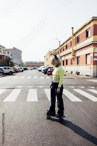 Diverse young woman outdoors city living riding longboard skateboarding carefree