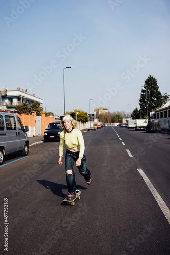 Young diverse rebel alternative queer woman skating riding longboard outdoor