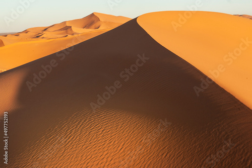 Paesaggio desertico con dune di sabbia alte e sfondo cielo blu