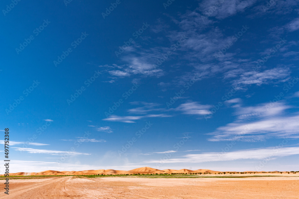 Paesaggio desertico con dune di sabbia alte e sfondo cielo blu Paesaggio desertico con dune di sabbia alte e sfondo cielo blu