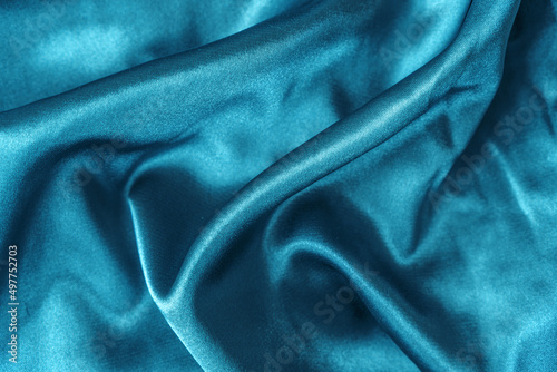 Elegant smooth blue silk or satin folds closeup. Cloth texture background. Abstract wallpaper. Trendy dark skyblue backdrop for web design. Luxury twisted fabric backplate 