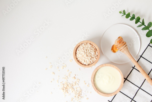 Natural ingredients for homemade face mask, top view of yoghurt, oat and honey on white background, beauty skincare product concept, flat lay