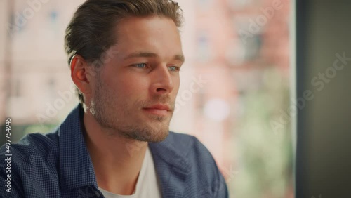 Close Up Portrait of a Happy Young Adult Male with Light Combed Hair and Beard Posing for Camera. Handsome Diverse Caucasian Male Smile and Pose for Camera. Working on Computer at Home. photo