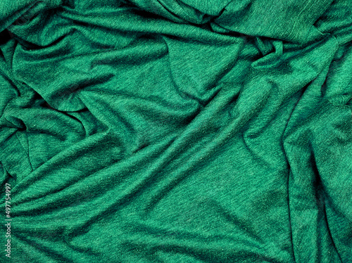 green creased fabric texture background, empty green cloth use as wallpaper. simple wavy t-shirt structure, plain fashion clothes unprinted design. luxury, christmas concept background.