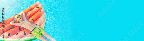 Summer vacation banner of happy nine years old boy (kid, child) in yellow sunglasses on inflatable ring (air mattress) in swimming pool at hotel. Resort, family beach holiday. photo