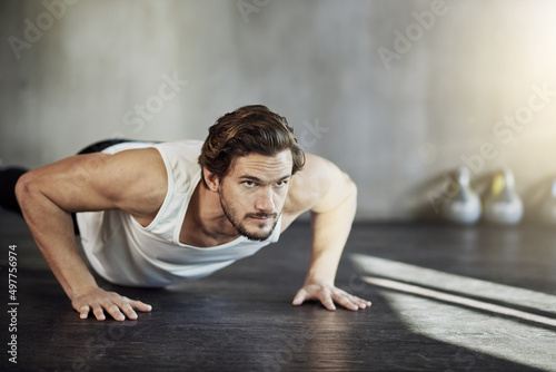 Getting stronger with every rep. Shot of a handsome young man doing pushups as part of his workout.