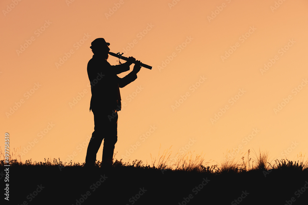 silhouette of pimak playing flute outdoors in nature silhouette of pimak playing flute outdoors in nature