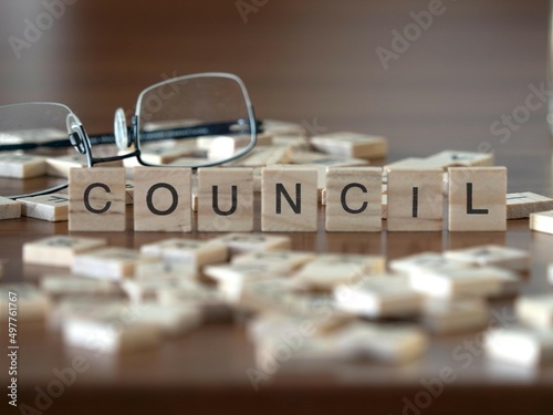 council word or concept represented by wooden letter tiles on a wooden table with glasses and a book