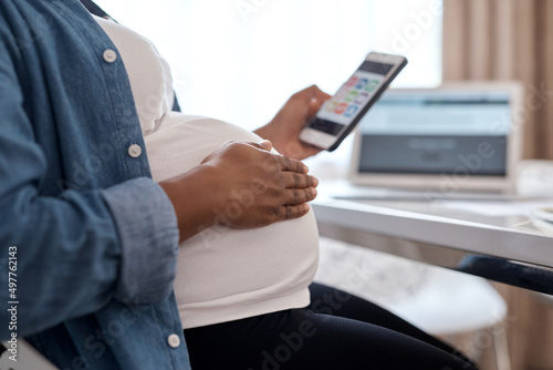 This app has helped me so much through my pregnancy journey. Cropped shot of a pregnant woman using her cellphone while sitting at home. © N Felix/peopleimages.com