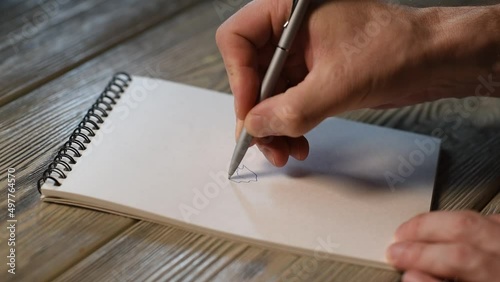 Hand tremor test in a patient with Parkinson's disease. A man's hand with a pen draws a spiral on a piece of paper close-up.