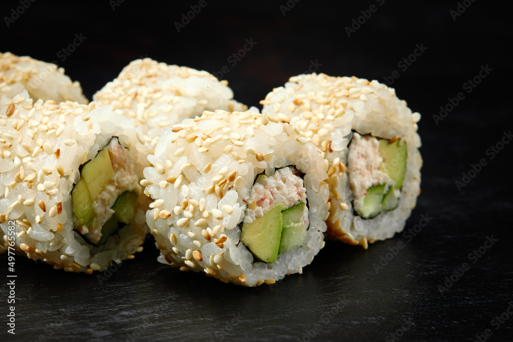 Traditional delicious fresh sushi roll set on a black background. Sushi roll with rice, cream cheese, avocado, salmon, sesame. Philadelphia. Sushi menu. Japanese kitchen, restaurant. Traditional delicious fresh sushi roll set on a black background. Sushi roll with rice, cream cheese, avocado, salmon, sesame. Philadelphia. Sushi menu. Japanese kitchen, restaurant.
