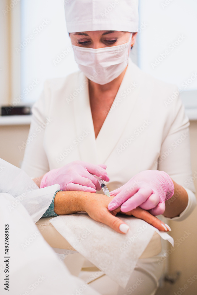 Hypodermic injections with a filler needle - renewal of the condition of the skin of the hands in an older woman Hypodermic injections with a filler needle - renewal of the condition of the skin of the hands in an older woman