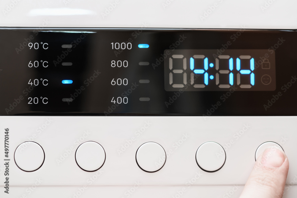 Washing machine display close up ,time remaining four hour 14 minutes during washing process. Finger selects wash mode. Abstract laundry programming backdrop Washing machine display close up ,time remaining four hour 14 minutes during washing process. Finger selects wash mode. Abstract laundry programming backdrop