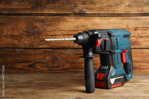 Modern electric power drill on wooden table, space for text photo