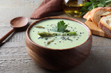 Bowl of delicious asparagus soup on wooden table