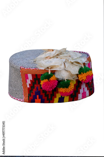 closeup the colorful hand made himachali indian traditional cap with hanging white flowers isolated on white background. photo