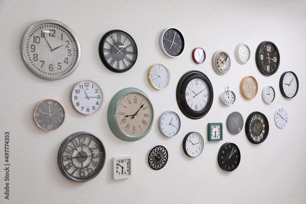 Collection of different clocks hanging on white wall