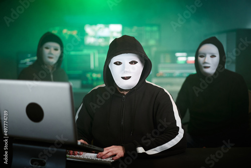 Masked Hacker is Using Computer for Organizing Massive Data Breach Attack on Corporate Servers. They're in Underground Secret Location Surrounded by Displays