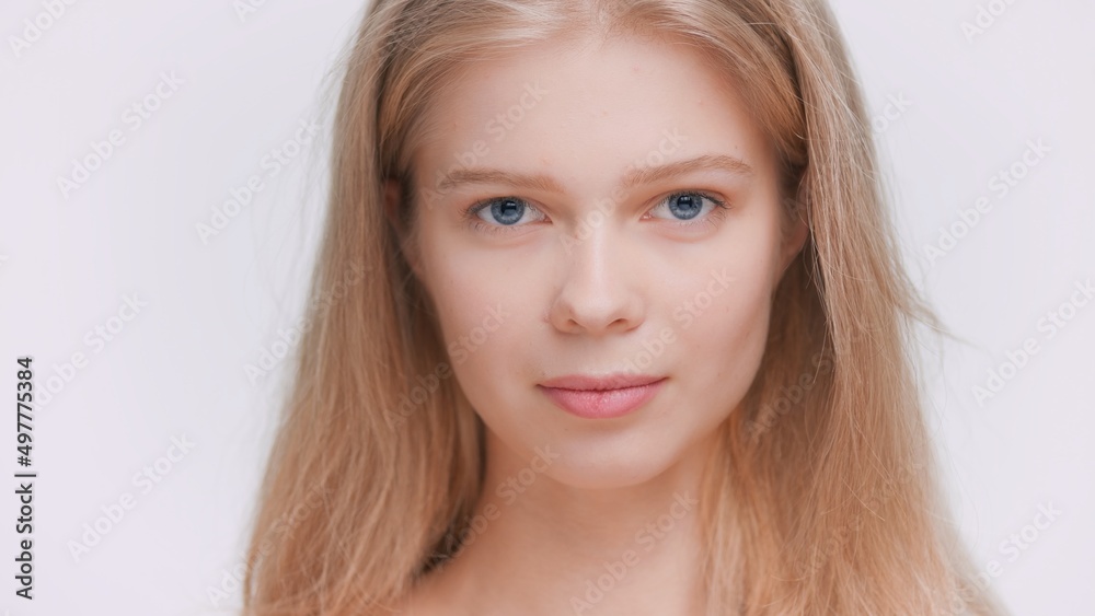 Beauty portrait of young blonde beauty model with blue eyes looks at the camera on grey background | Skin care commercial concept Beauty portrait of young blonde beauty model with blue eyes looks at the camera on grey background | Skin care commercial concept
