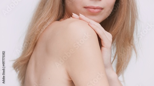 Young blonde female beauty model demonstrates her perfect skin  touching her shoulder   Skincare product advertising concept.