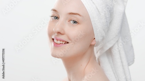 Beauty portrait of young attractive ginger woman with a towel on her head looking at camera and smiling on white background   Face care concept