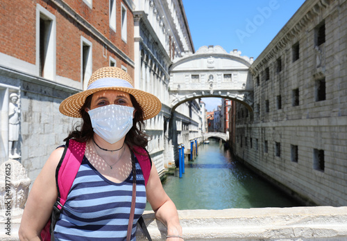 Pretty woman with mask during lockdown in Venice in Italy and the Brdige of SIGHS in background