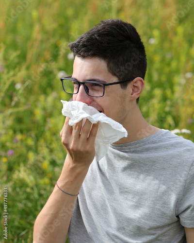 Fotografia boy with glasses sneezing with a handkerchief because he has allergy