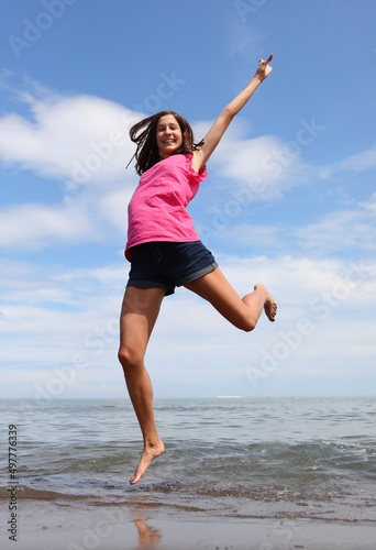 Fototapeta Naklejka Na Ścianę i Meble -  happy little girl jumping on the beach by the sea