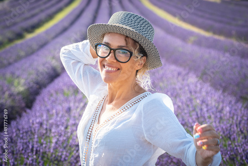 Portrait of happy young woman smiling and enjoying leisure outdoor activity with lavender field flowers in background. Travel and summer holiday vacation tourit female people. Attractive joy lady photo