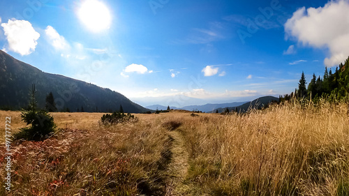Panoramic view on Mur valley from Seckauer Zinken in the Lower Tauern in Styria, Austria, Europe. Sunny golden autumn day in Seckau Alps. Hiking trail on dry and bare grassland terrain. Soft hills