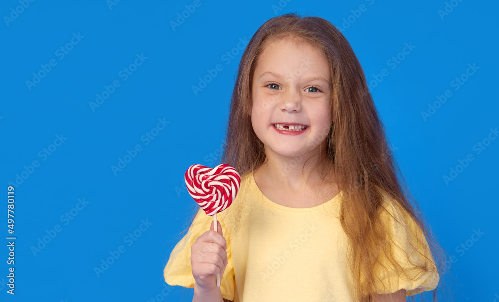 Toothless child. Cute little girl smiles broadly with lollipop in hands. The first milk tooth fell out. Carefree childhood concept and dental hygiene Toothless child. Cute little girl smiles broadly with lollipop in hands. The first milk tooth fell out. Carefree childhood concept and dental hygiene