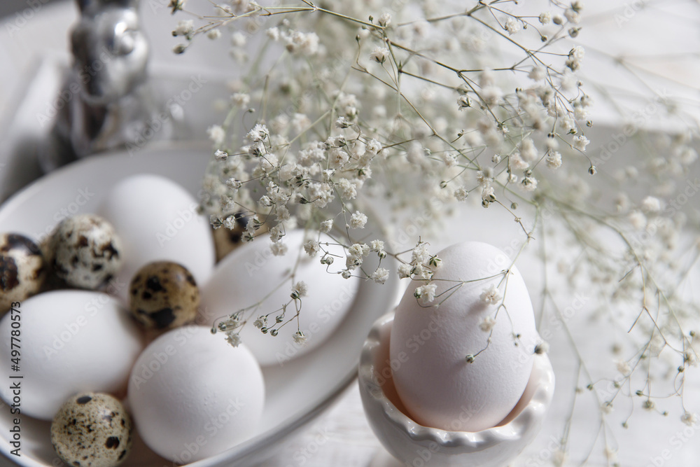 Table decorated for Easter in beige tones. Dried gypsophila, chicken and quail eggs, a silver figurine of a hare and a cup of coffee. Easter concept. Table decorated for Easter in beige tones. Dried gypsophila, chicken and quail eggs, a silver figurine of a hare and a cup of coffee. Easter concept.