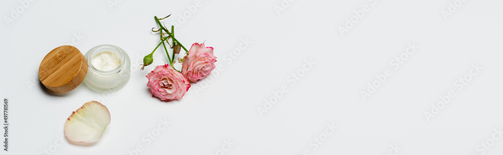 pink flowers near container with cream on white, banner. pink flowers near container with cream on white, banner.
