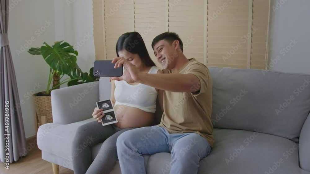 Young pregnant woman with husband embracing and video call with family and friends by smartphone on social media, family and pregnancy care concept Young pregnant woman with husband embracing and video call with family and friends by smartphone on social media, family and pregnancy care concept
