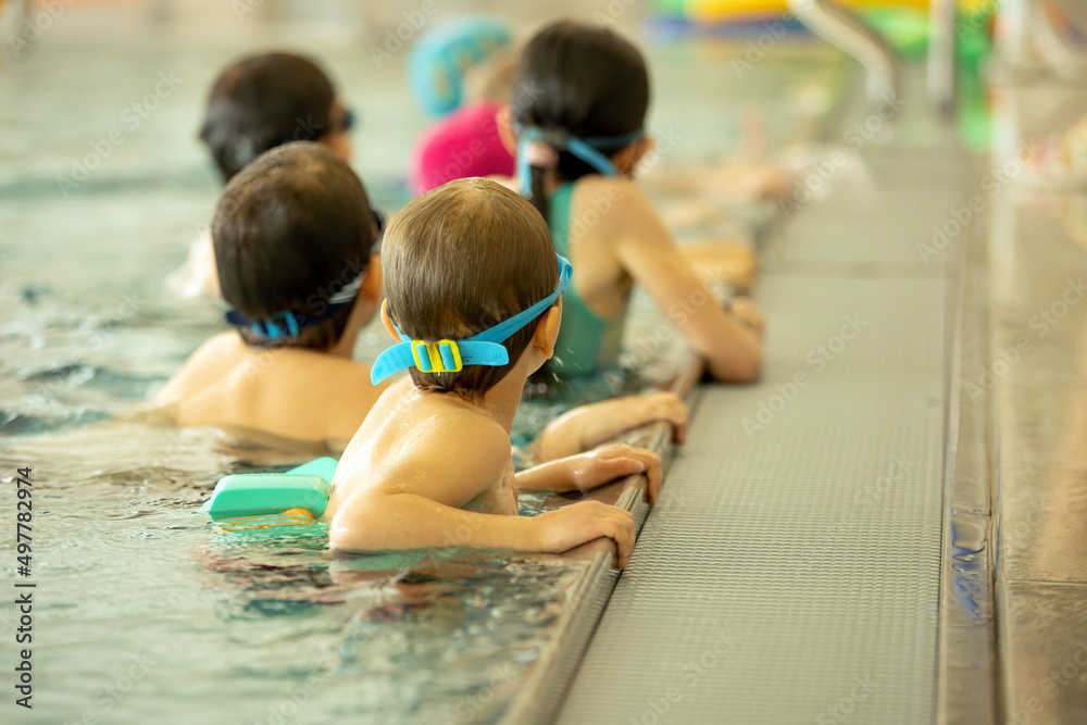 Obraz premium Child, taking swimming lessons in a group of children in indoor pool
