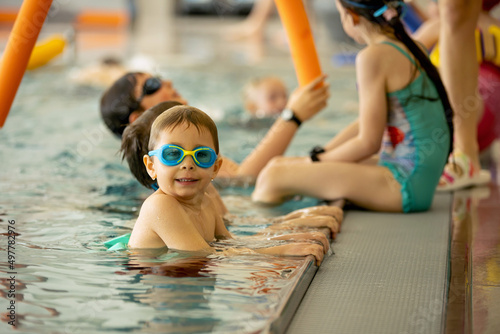 Fotografie, Obraz Child, taking swimming lessons in a group of children in indoor pool