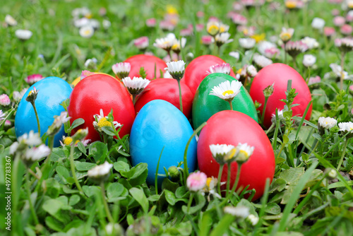 Close up of colored easter egg placed on green grass and colorful spring flowers. Colored eggs is an old Easter tradition that was developed on Romanian soil with great craftsmanship.