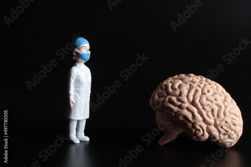 miniature figurine of a surgeon doctor with a giant human brain on a black background