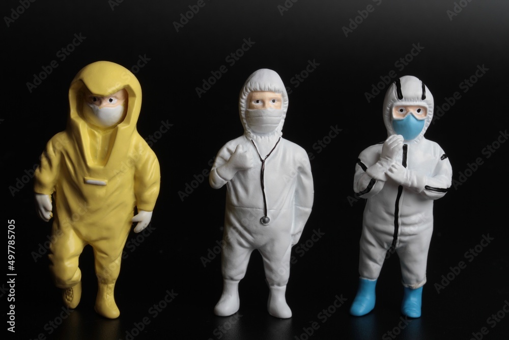 miniature people with protective suits and masks on a black background miniature people with protective suits and masks on a black background