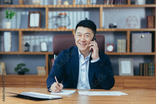 Fotografija Successful paper boss in office looks at camera and smiles, asian businessman