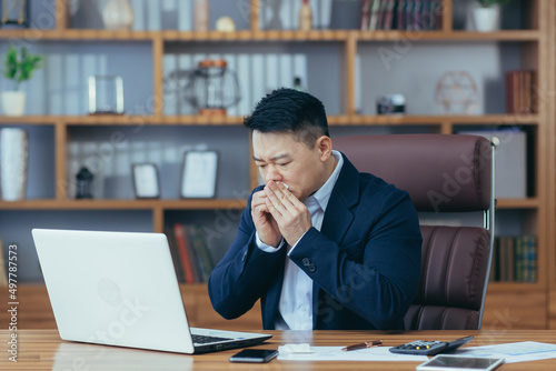 Businessman working in the office, sick Asian has a cold and flu, runny nose from allergies