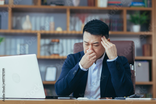 Businessman working in the office, sick Asian has a cold and flu, runny nose from allergies © Liubomir