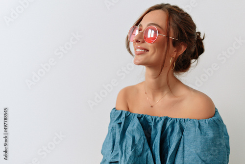 Happy caucasian young girl is looking at window while posing against white wall