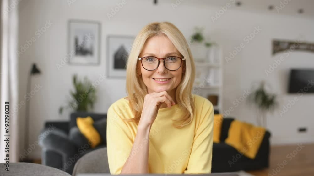 Intelligent mature senior female business owner in glasses looking at the camera, sitting at the desk in front of laptop, successful businesswoman enjoying loving her job, ready for the next challenge Intelligent mature senior female business owner in glasses looking at the camera, sitting at the desk in front of laptop, successful businesswoman enjoying loving her job, ready for the next challenge