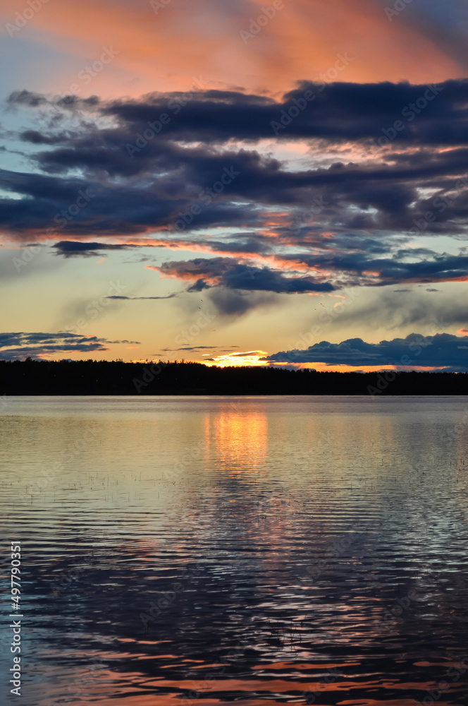 Colourful sunset over the lake in Norway. Orange, red, blue colors in Nordic sky reflecting in the water Colourful sunset over the lake in Norway. Orange, red, blue colors in Nordic sky reflecting in the water