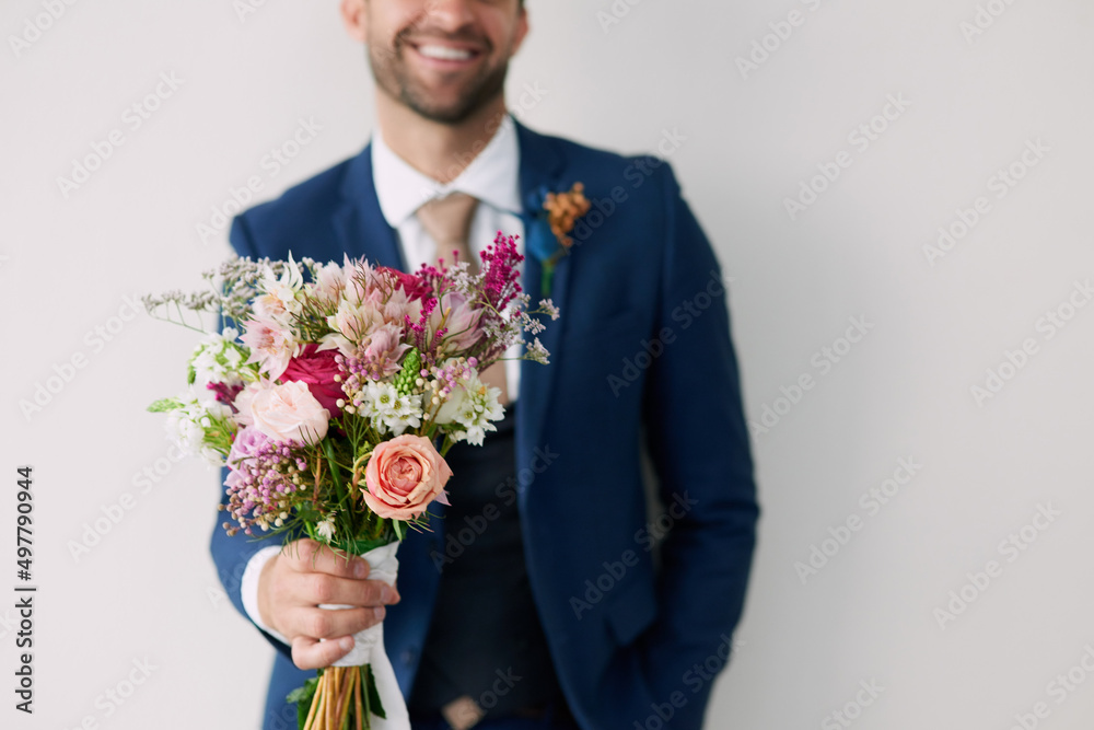 The flowers that won her heart. Studio shot of a handsome young groom holding a bunch of flowers a gray background. The flowers that won her heart. Studio shot of a handsome young groom holding a bunch of flowers a gray background.