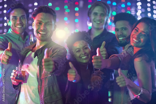 Friday night done right. Portrait of a happy group of friends giving a thumbs up while standing in a nightclub.