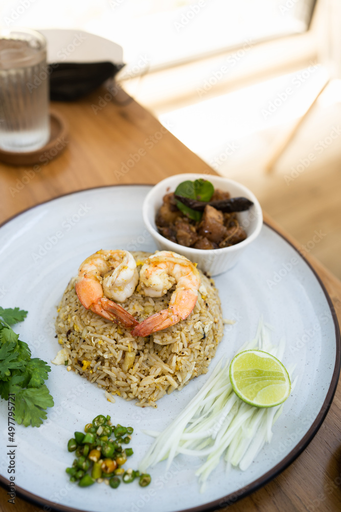 A view of a plate of shrimp fried rice in wood table on a restaurant . Top view. Delicious and easy menu.