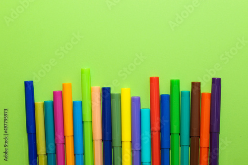Multi-colored stationery felt-tip pens on a background of multi-colored cardboard paper.